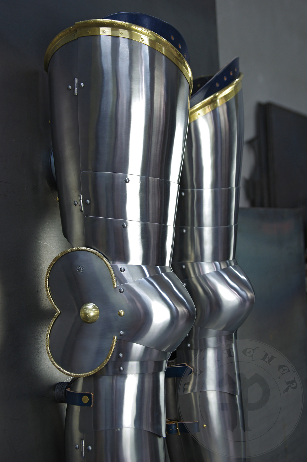 Late 14th/early 15th c. style full plate leg harness with brass decorations with a geometrical, hand filed pattern. Material: medium carbon and spring steel of various thickness: 1 mm; 1,2 mm and 1,5 mm; brass; vegetable tanned leather. Heat treatment: cuisses (thigh plates, lames, poleyns and demi-graves) heat hardened and tempered up to 42 HRC.